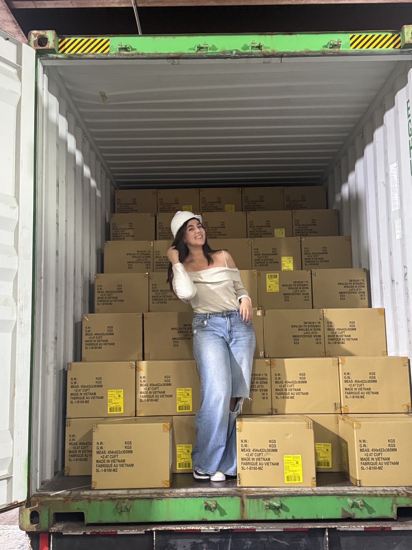 Valeria Bernardo, con casco blanco, apoyada en una pila de cajas dentro de un contenedor marítimo abierto.